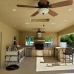 A kitchen with a ceiling fan and some chairs