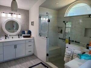 A bathroom with a shower, sink and mirror.
